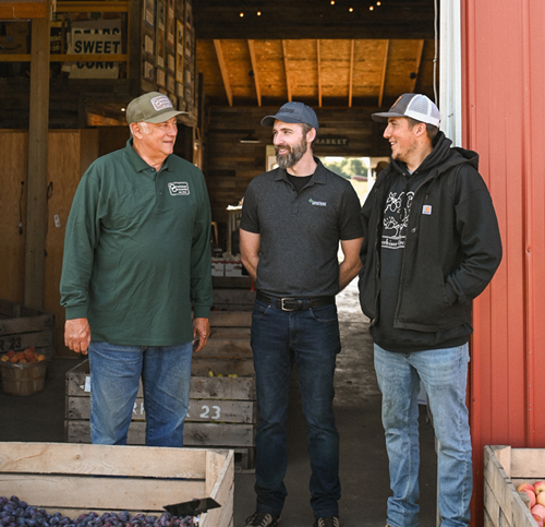 The Overhiser's and their Crop insurance agent, Jeffery Sparks standing in front of a red barn