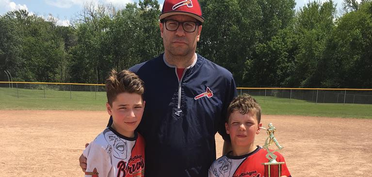 Jim, Ivan, and Roland Kosmerick stand at a baseball field.