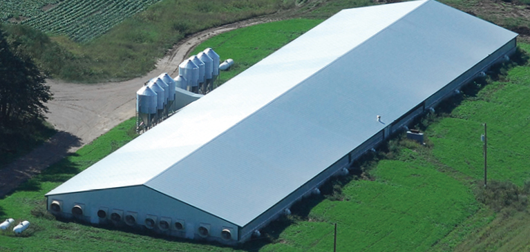 Bird’s eye view of farm with long, new pole barn and holding tanks.  