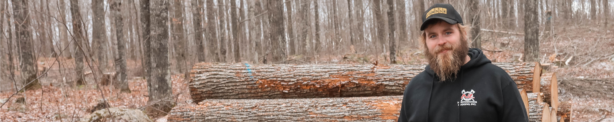 Man in front of stack of logs