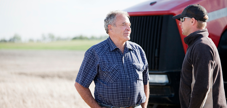 Two men talking in front of tractor