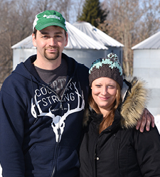 Two farmers standing in front of their farm in the snow