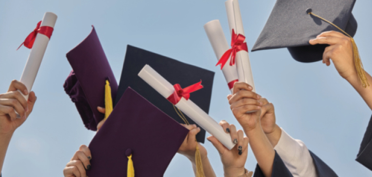 Students at graduation holding caps and diplomas