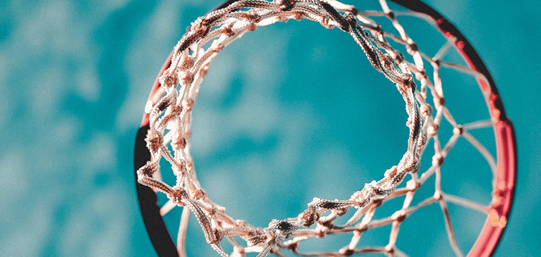 View from bottom of basket ball and net looking up into clear blue sky.