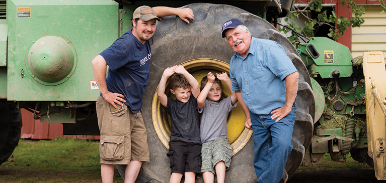 Four people standing next to a tractor
