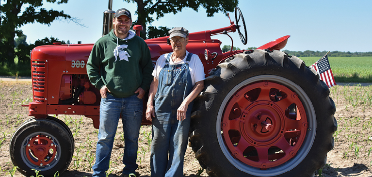 2 men standing next to a tractor 