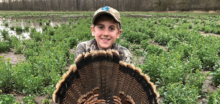 Boy with turkey in a field.