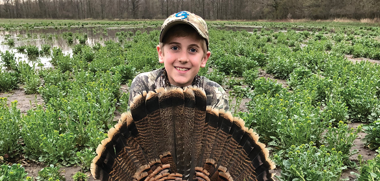 Boy with turkey in a field. 