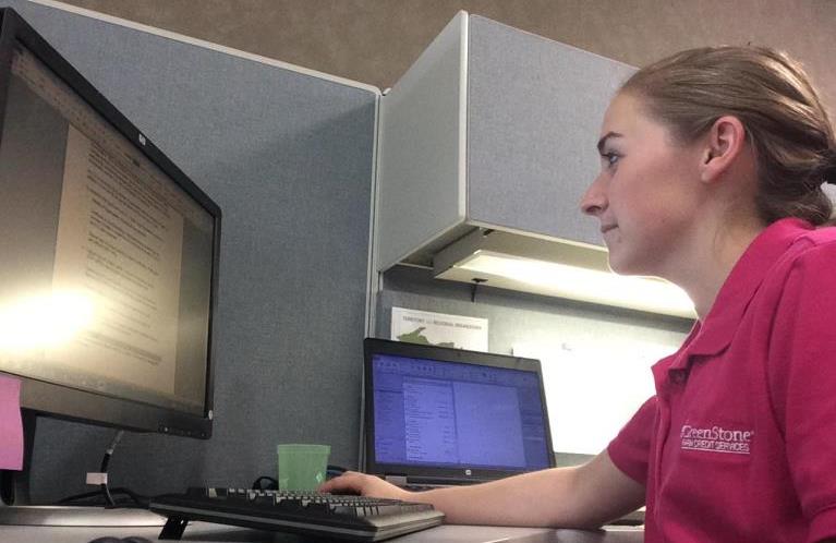 Abbey in front of the GreenStone sign at the Adrian branch
