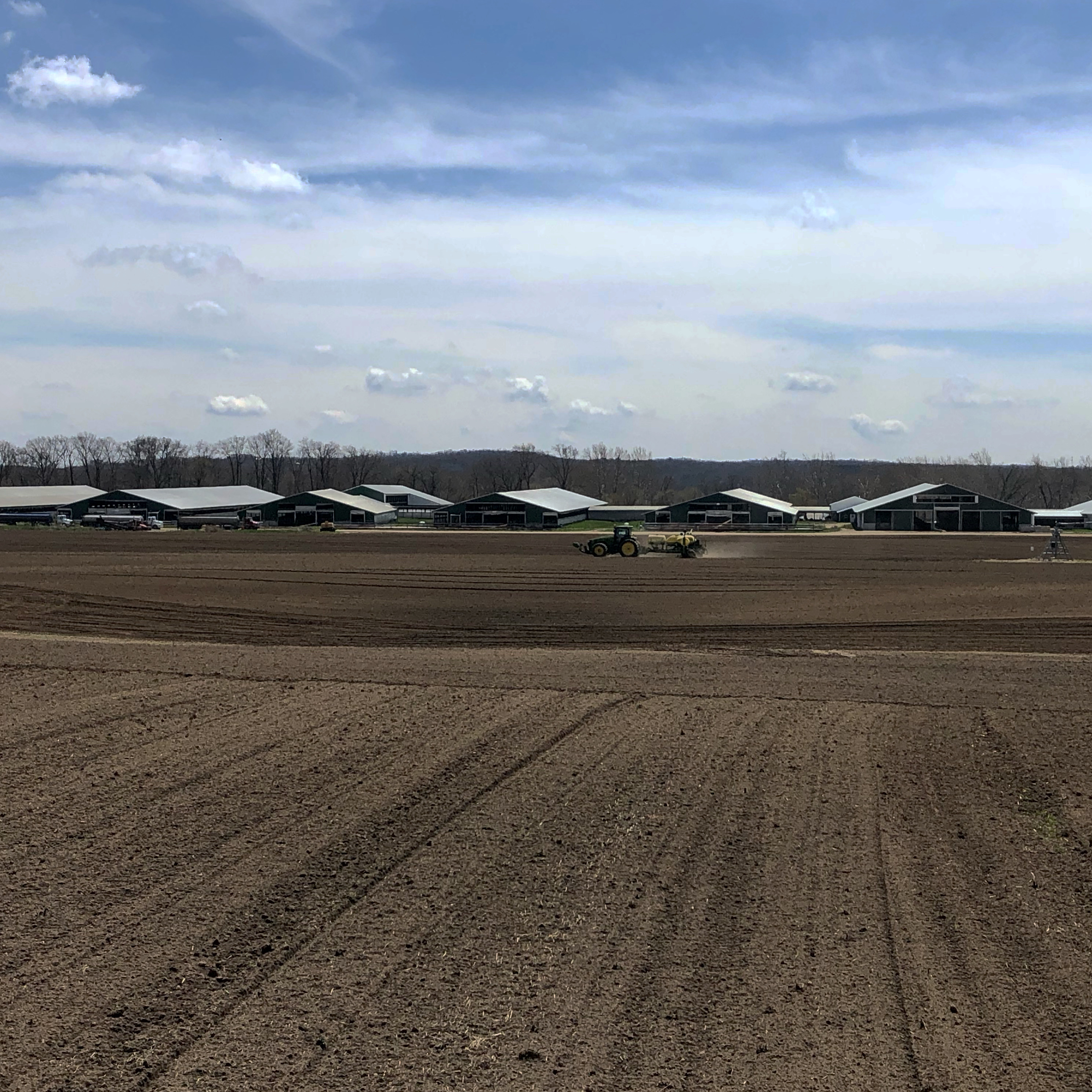 Tractor plowing field with Sand Creek Dairy in the background