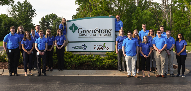 Class of 2019 interns standing together in front of GreenStone's corporate office sign by road