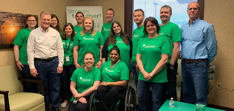GreenStone employees wearing green on Patronage Day standing in front of banner at St. Johns branch