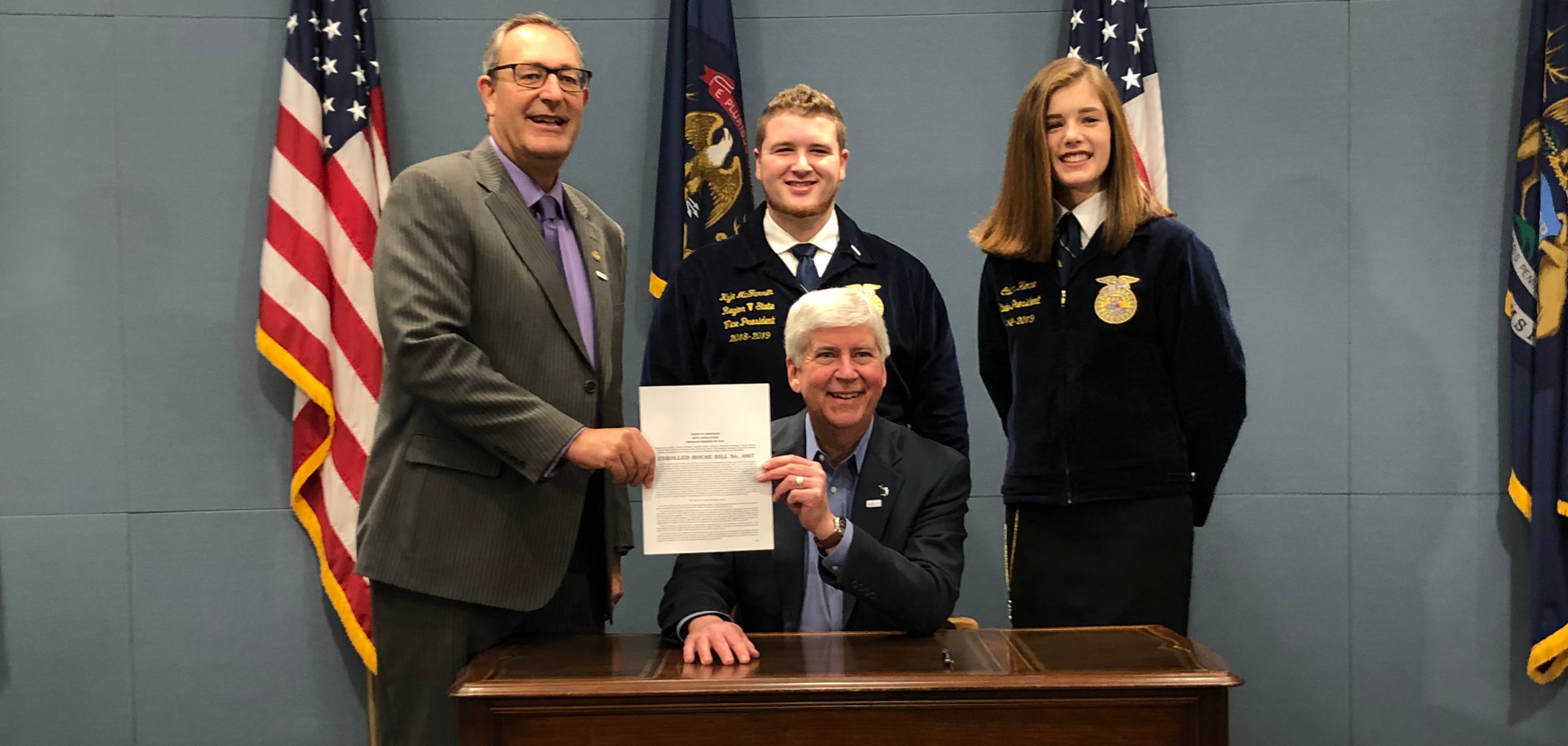 FFA student officers standing behind Governor and legislature man holding bill