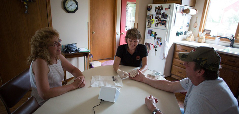 Couple sitting with nurse from Rural health initiative at kitchen table