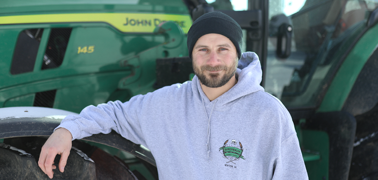 Male farmer leaning on a tractor