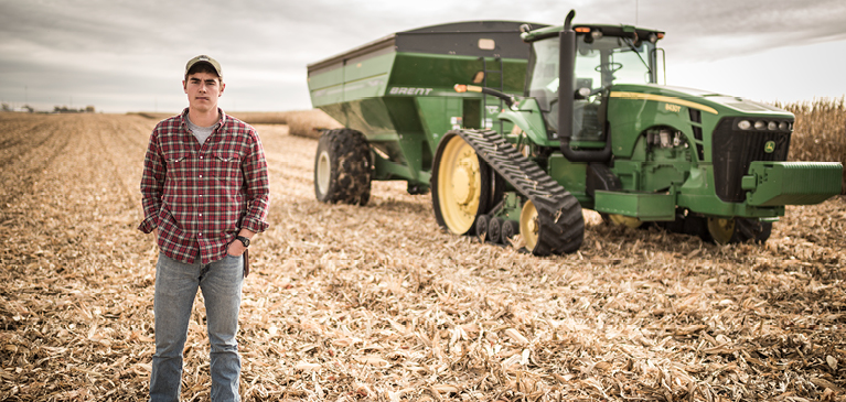 Farmer standing in front of field and combine tractor
