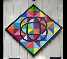 Loren and Becky Roslund's family farm barn quilt block with a Swedish colorful, geometric-print background with black Irish Celtic knot overlay.