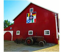 Beautiful red barn at the DeFever family farm. The quilt has four flags, one in each corner, representing the different heritages of the family.