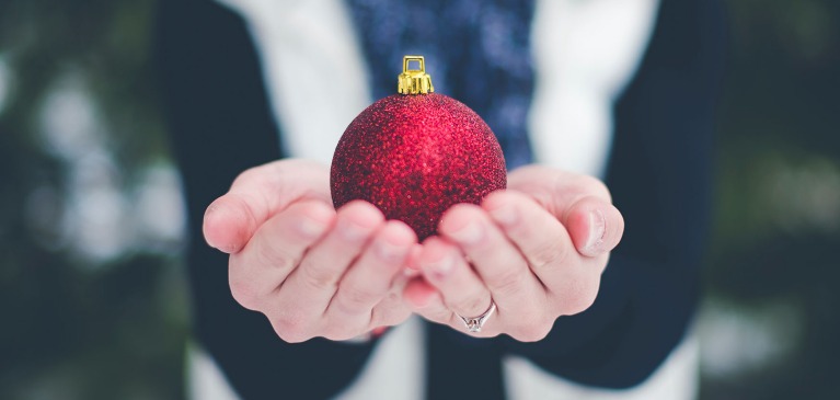 Hands holding red Christmas ornament