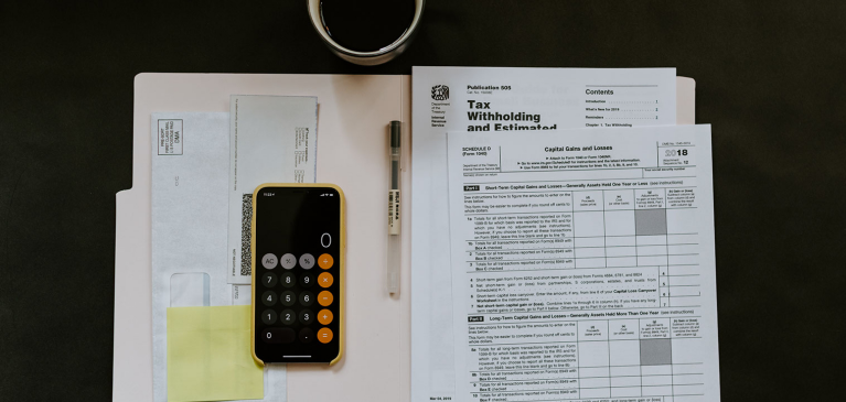 Tax papers on desk with calculator and coffee mug