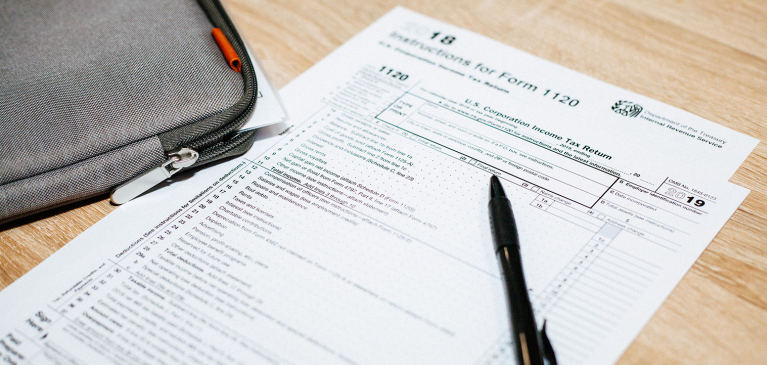 Tax forms on light colored desk with pen