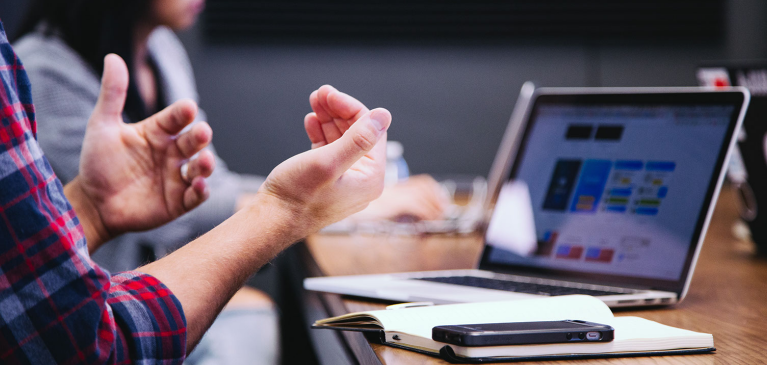 Two people talking by a laptop