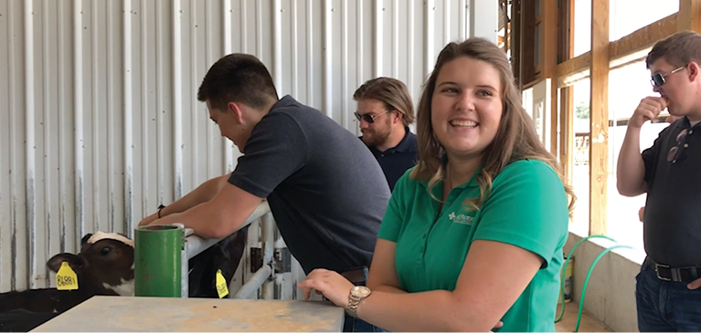 Smiling young girl among other teens in dairy barn