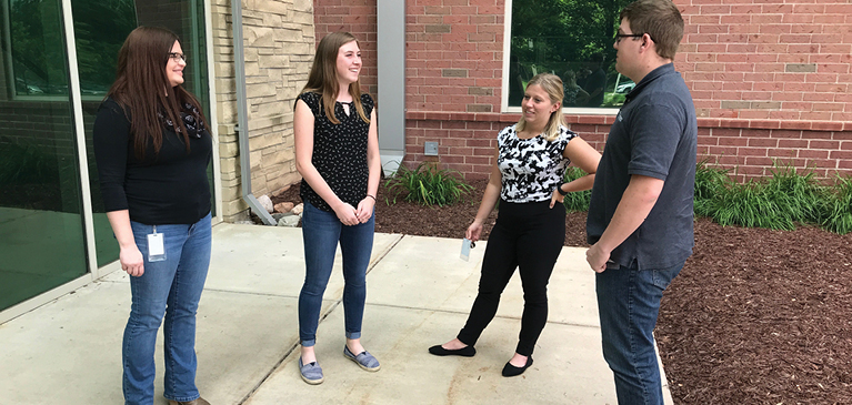 Interns Jennifer Pawlowski, Alex Herold, Hannah Cameron and Devon Davidson talking in front of GreenStone HQ