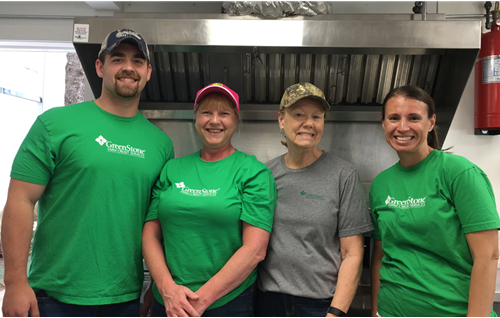 GreenStone employees standing in front of large stove in kitchen