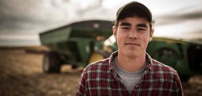 081517-effective-succession-planning-five-key-considerations Young farmer in front of grain cart
