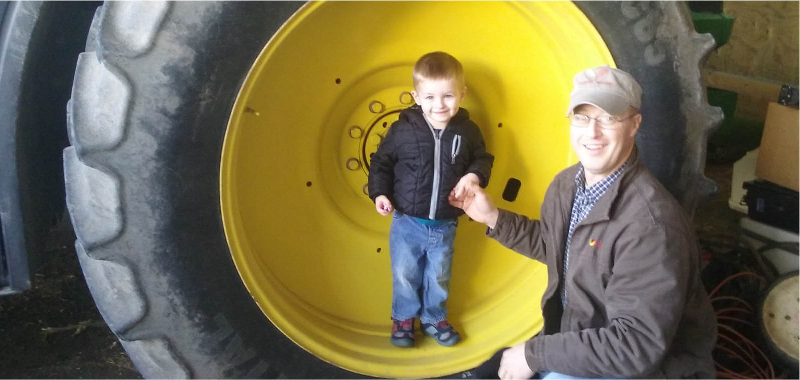 Farmer and his son by tractor tire