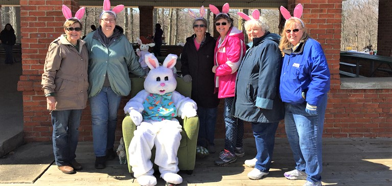 Women of the St. Johns Lioness Club standing under a pavilion at the annual Easter Egg Hunt with the Easter Bunny.