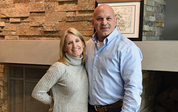 Surrounded by nature couple standing in front of large fireplace in house they built