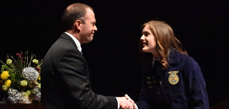 Travis Jones shaking hands with Caitlin Henne