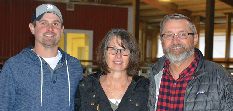 Photo of two men and a woman in a barn.