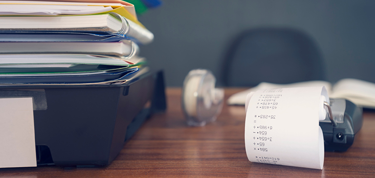 stack of folders next to a receipt calculator