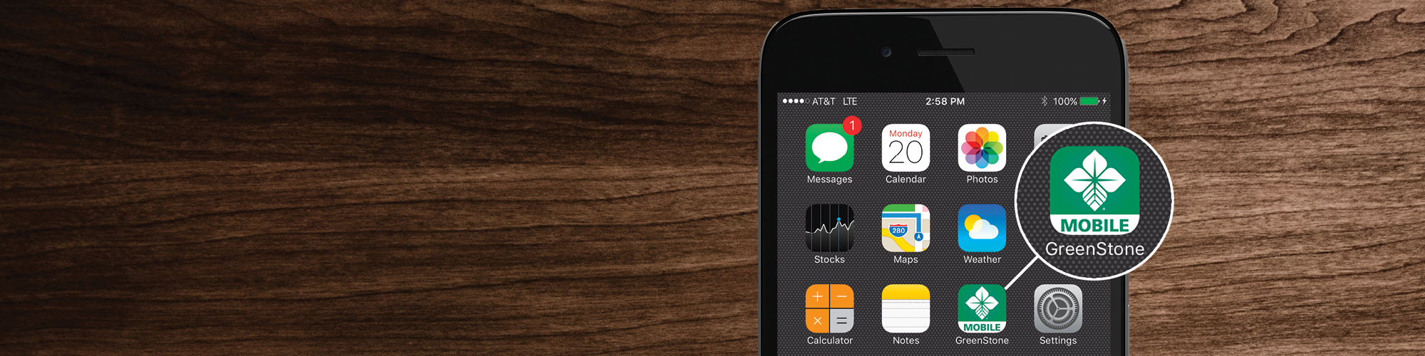 Phone highlighting GreenStone app on wood background