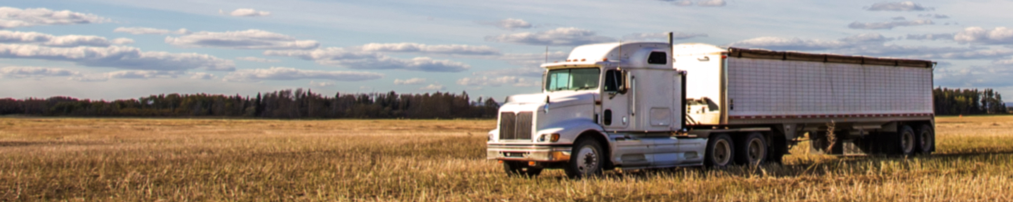 Semi-truck hauler driving through farm field