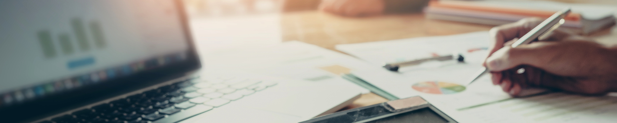 Close up of a computer and adviser reviewing financial forms