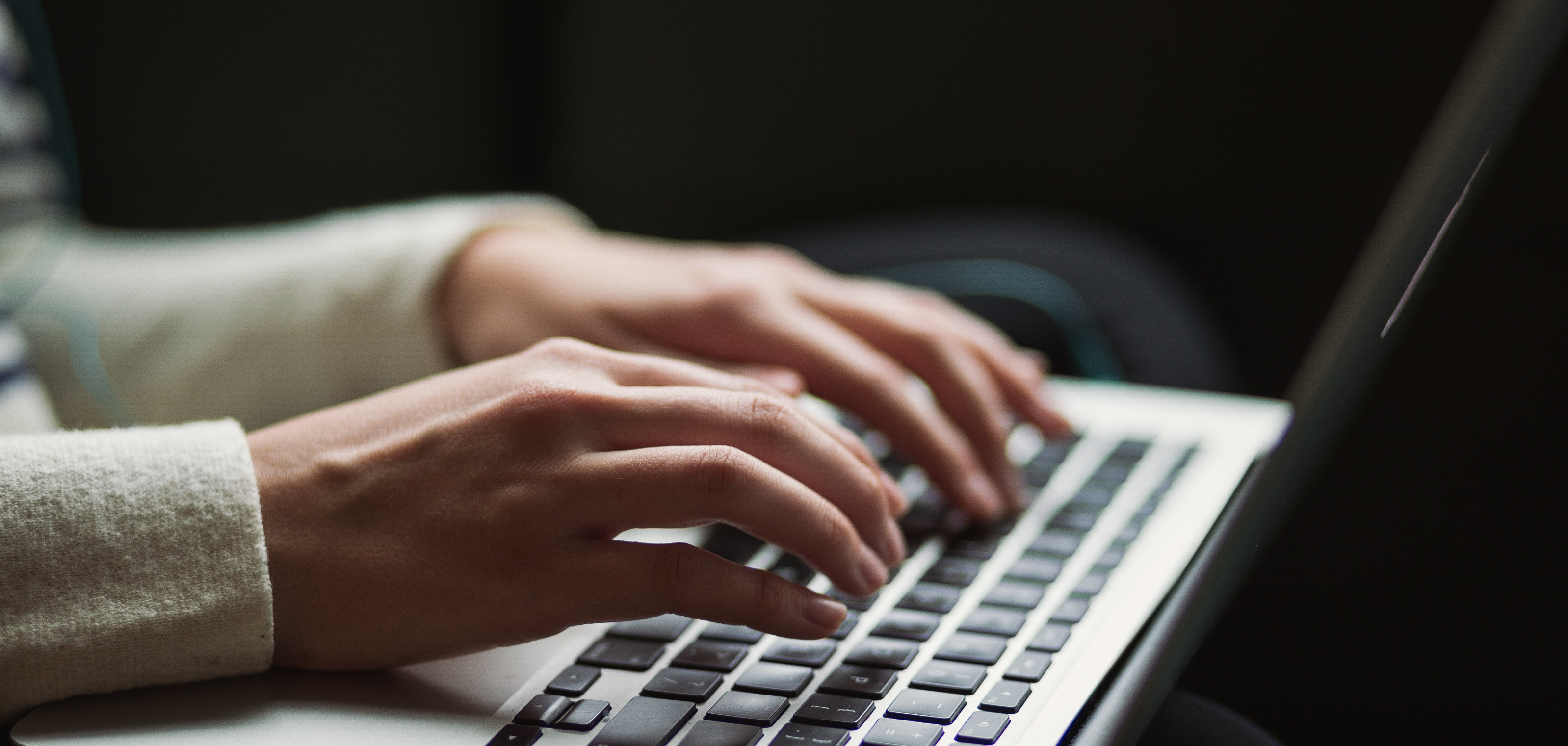 Person's hands typing on a laptop keyboard