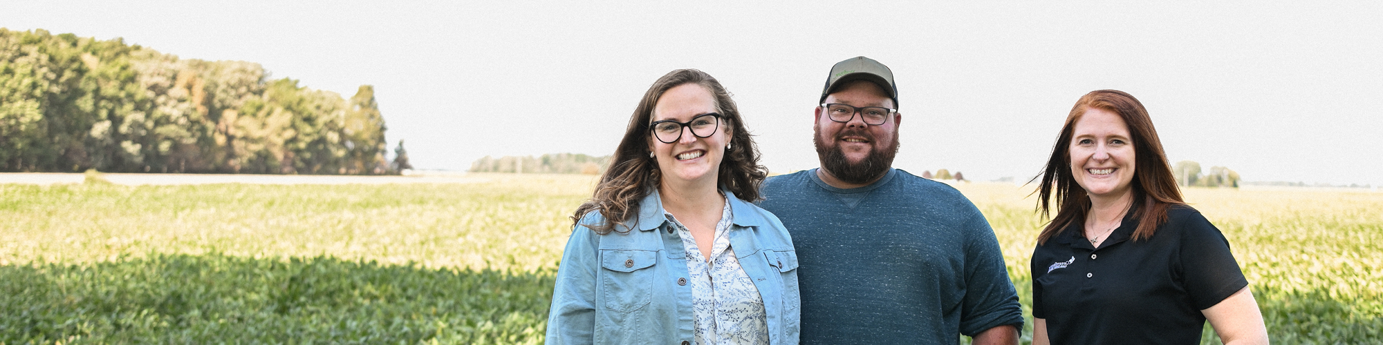 Two women and a man standing in a feild