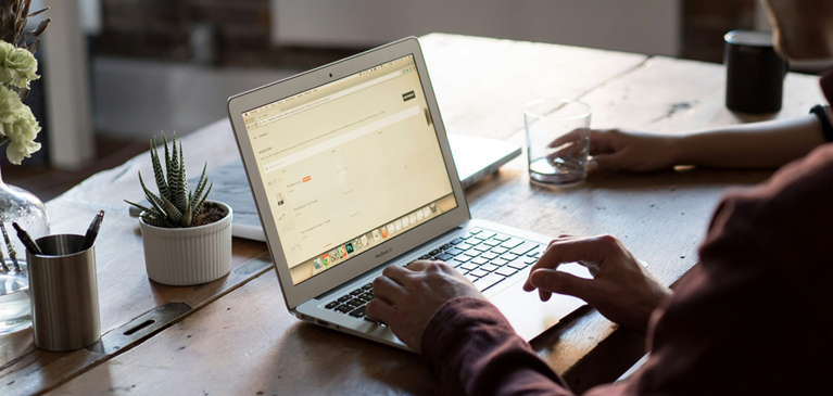 Person working from a laptop on a wooden table