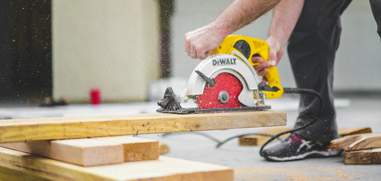 Man cutting a board with a hand saw