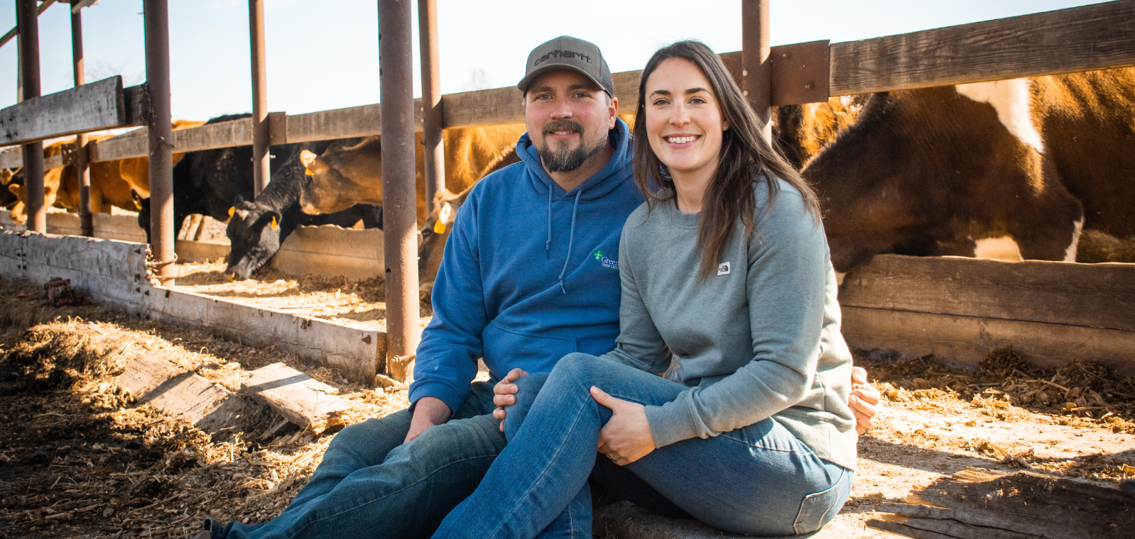 Man and a woman sitting outside a cow pen