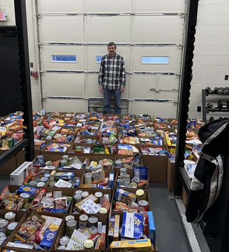Man standing behind bins of food that are being donated to charity