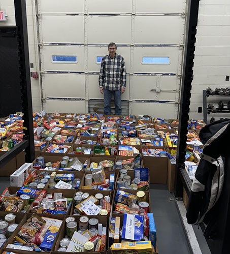 Man standing behind bins of food that are being donated to charity 