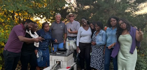 Nine people standing around a grill that they made in Africa