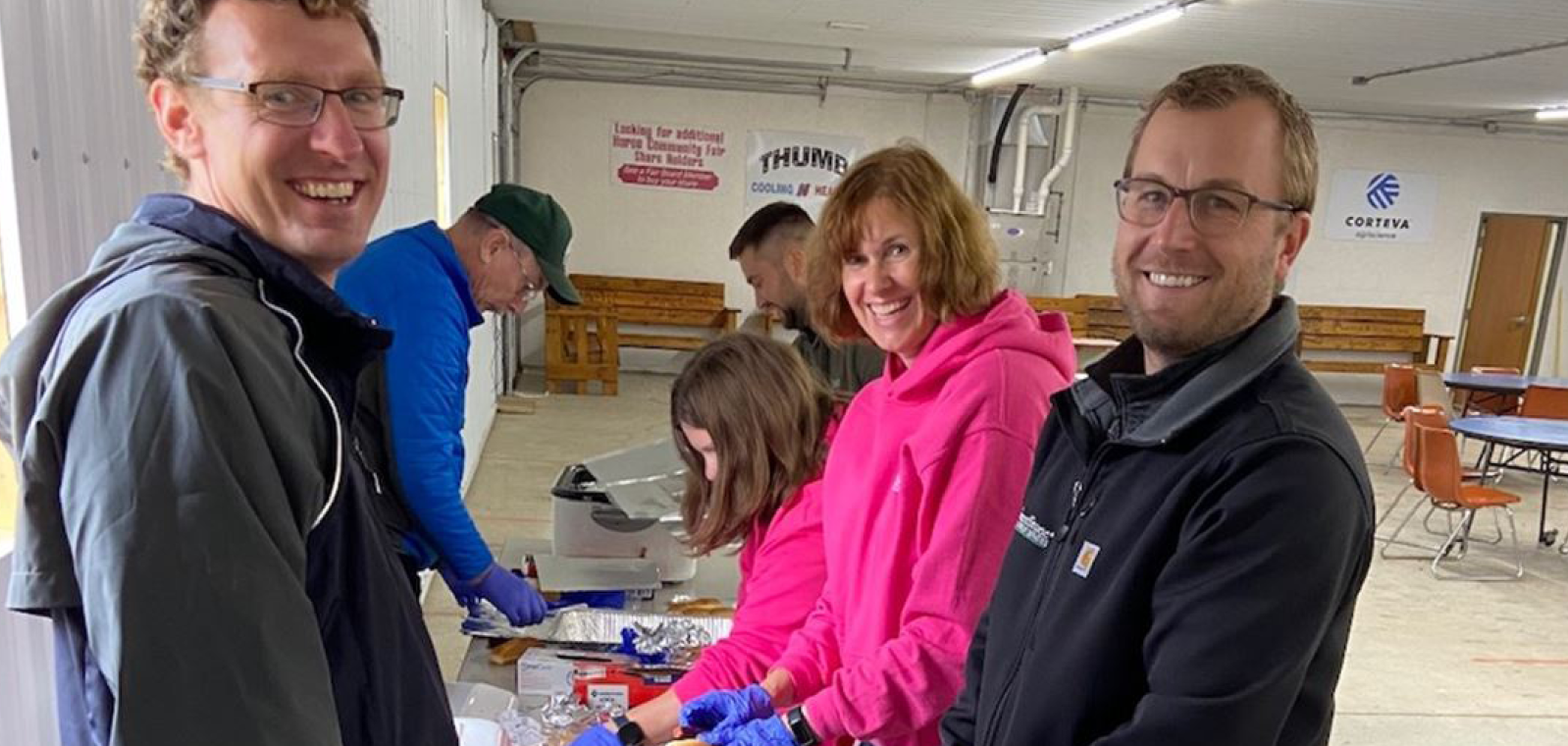 Five GreenStone employees preparing hot dogs for the kids. 