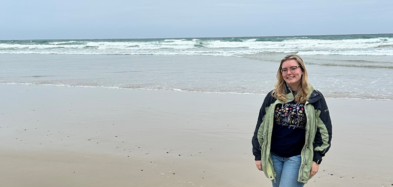 Woman standing in front of the ocean on a beach.