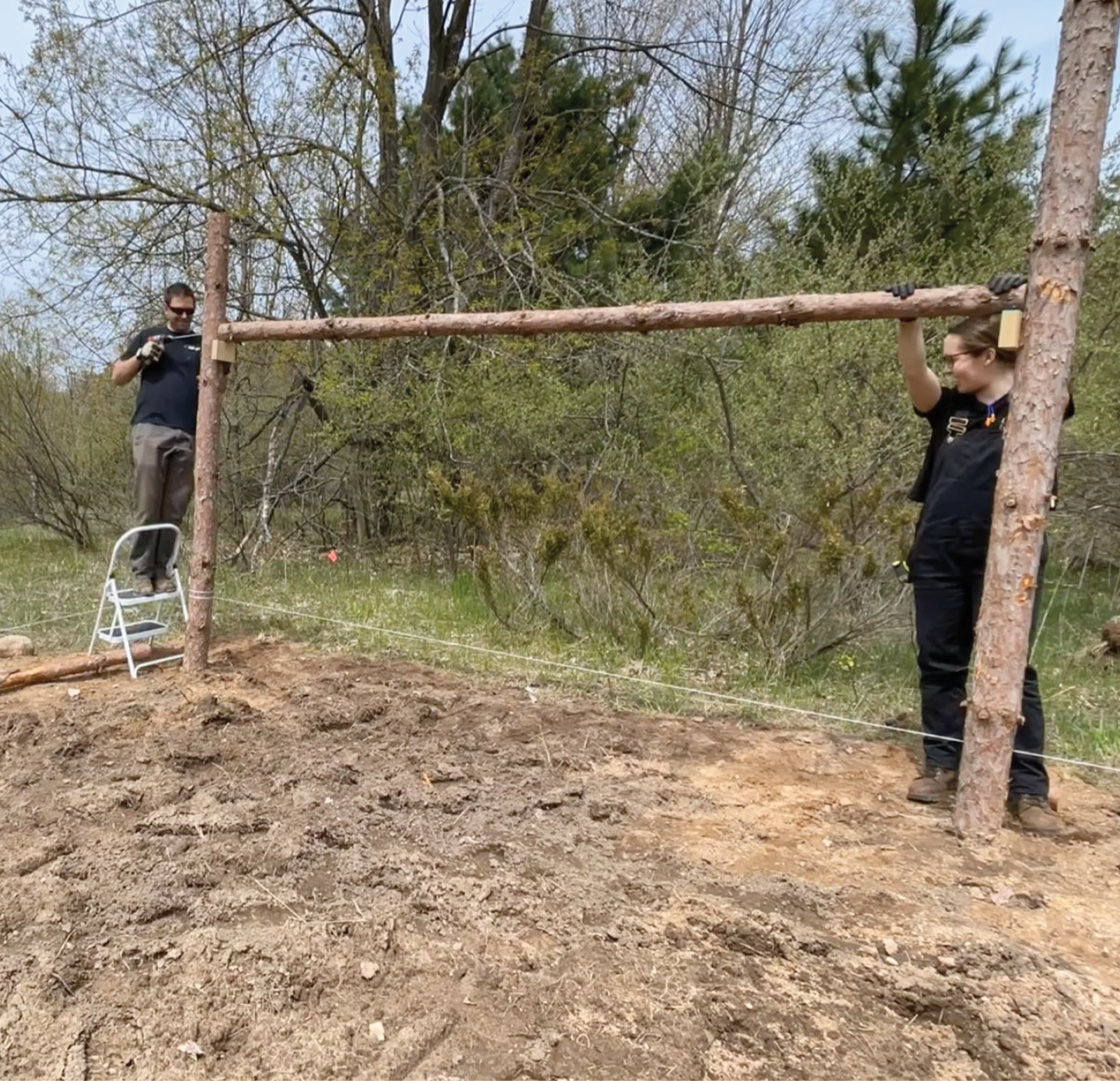 Two guys putting trellis poles up